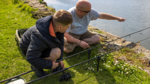 Bailiff teaches a young angler effective angling techniques during a junior angling session.