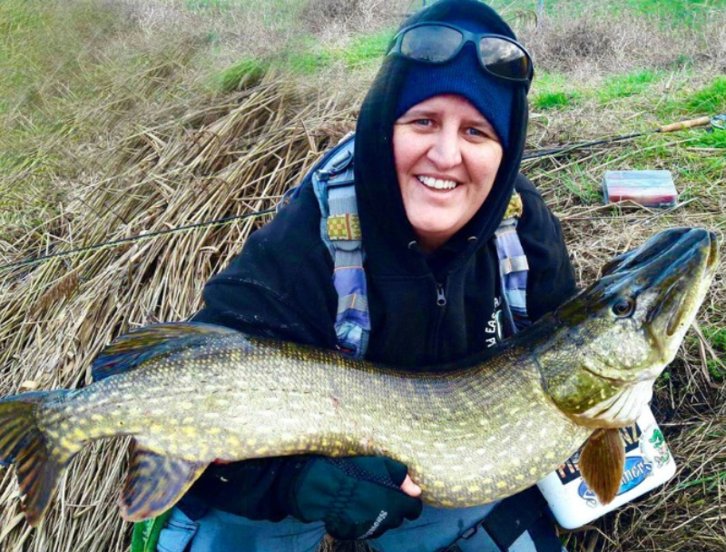 Barbara proudly holds a large pike after catching it on the fly at her local angling venue.