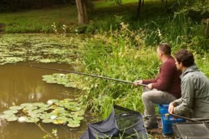 Two men on the riverbank with one rod waiting for a bite