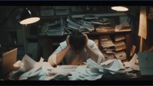 Fishery manager feeling overwhelmed surrounded by paperwork