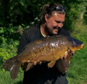 James Duffy holding an impressive common carp and smiling